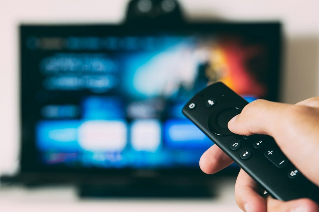 Smart TV con mando a distancia mostrando aplicación de streaming IPTV Smart TV con mando a distancia mostrando aplicación de streaming IPTV